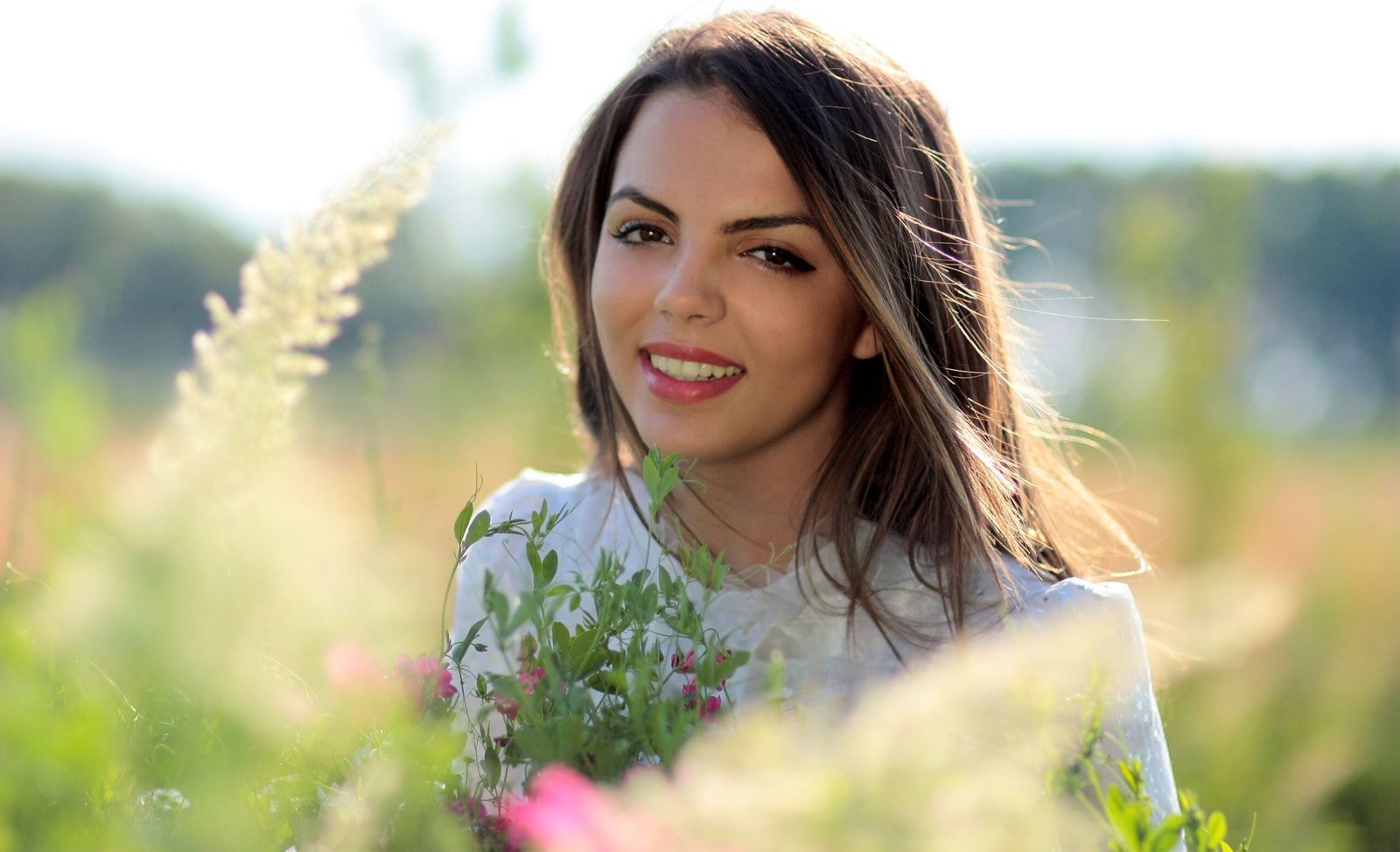 Portrait of a smiling woman with flowers in an outdoor setting, radiating happiness.
