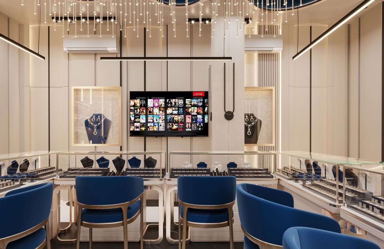 Modern jewelry store interior with elegant lighting and blue seating, showcasing luxury items in display cases.